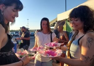 women eating pink elote Tucson Vegan Night Market