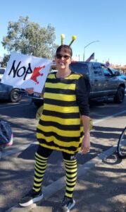 three women in yellow with signs at No Kings march