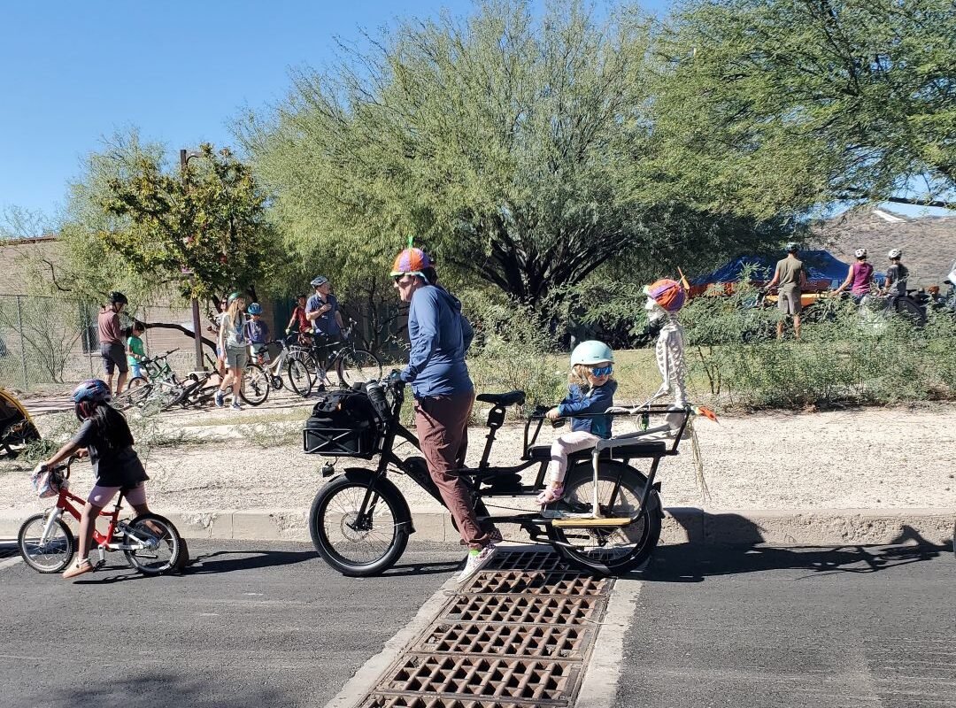 man and girl and skeleton riding on a bicycles at Tucson Cyclovia Oct 2026